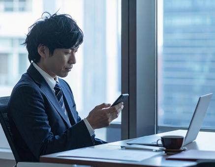 スマホを見る男性の写真