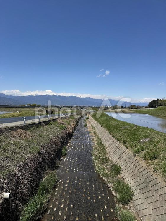 北アルプスと春の大沢川（長野県塩尻市） 大沢川,風景,空の写真素材