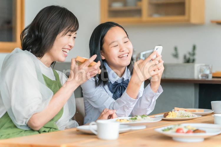 ママと一緒にスマホを見る子供・中学生 中学生,高校生,親子の写真素材