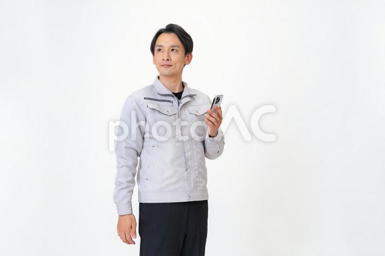 携帯を持つ作業着を着た男性 日本人,点検,保守点検の写真素材