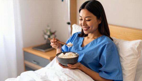 入院ベッドでご飯を食べる女性患者 入院ベッドでご飯を食べる女性患者の写真