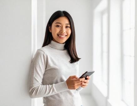 室内でスマートフォンを持ち笑顔の女性 室内でスマートフォンを持ち笑顔の女性の写真