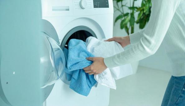 洗濯機から洗濯物を取り出す女性の手の写真