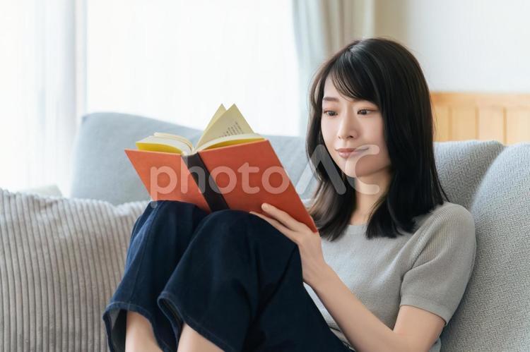 ソファに座って読書をする女性 女性,読書,本の写真素材