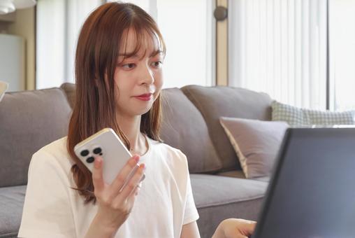 リビングでパソコンを操作する女性 リビングでパソコンを操作する女性の写真