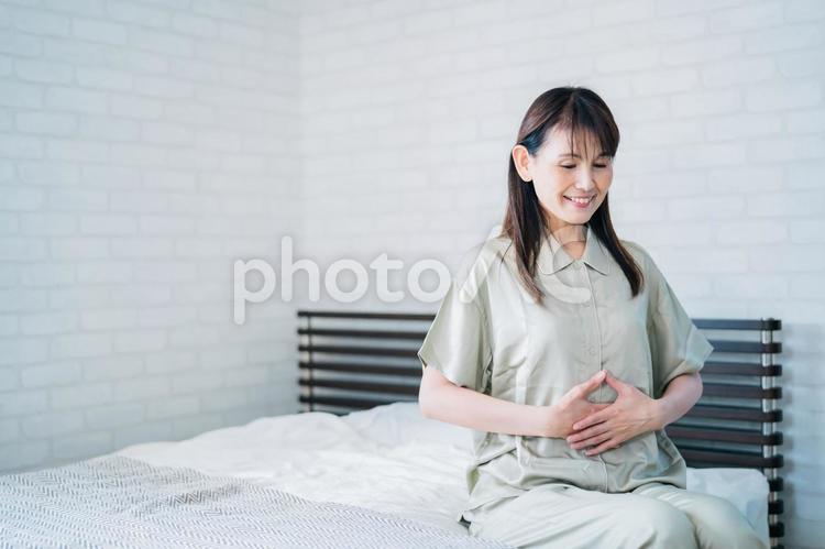 お腹を触るミドル世代の女性（笑顔） お腹,腸,腸活の写真素材