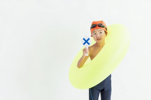 バツのプレートを持った水着を着た男の子 バツのプレートを持った水着を着た男の子 男の子,水着,白背景の写真素材