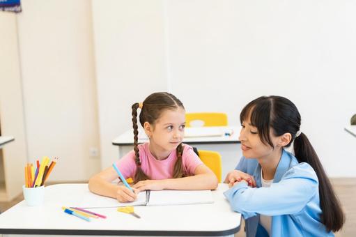 笑顔でしゃがんで見守る先生 女性,女の子,子どもの写真素材