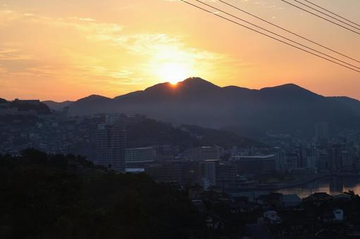 オレンジ色の空と山からの朝陽と市街地 オレンジ色の空と山からの朝陽と市街地の写真