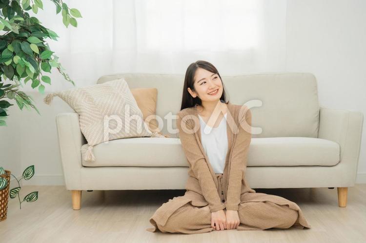 ソファの下に座る女性（笑顔） リビング,女性,ソファの写真素材
