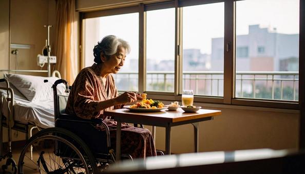 病室で車いすに座り食事をする高齢女性患者 病室で車いすに座り食事をする高齢女性患者の写真