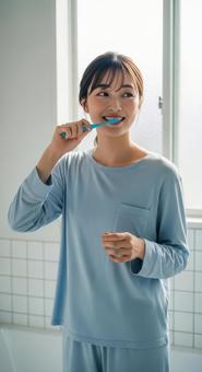 朝の洗面所で歯磨きをする若い女性 朝の洗面所で歯磨きをする若い女性の写真