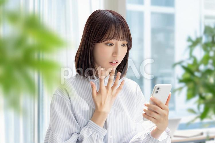 スマホの画面を見て驚く女性 女性,ビジネス,スマホの写真素材