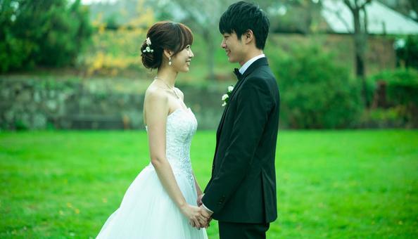 結婚式場の庭で手を取り合う新郎新婦の写真