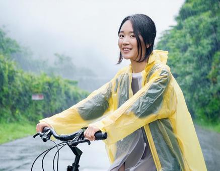 レインコートを着て自転車に乗る女性 レインコートを着て自転車に乗る女性の写真