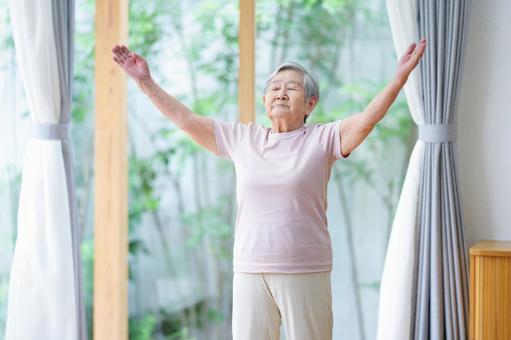 目を瞑り両手をあげポーズする高齢者 女性,目を瞑る,手をあげるの写真素材