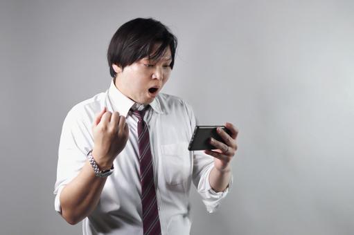 スマホに喜ぶ男性 ビジネスマン,男性,スマホの写真素材