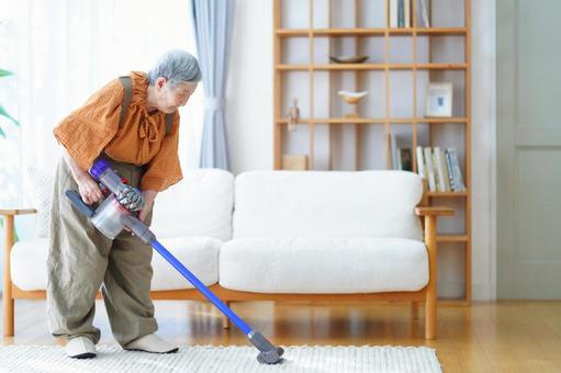 リビングの掃除機掛けをするおばあちゃん 女性,掃除,掃除機の写真素材