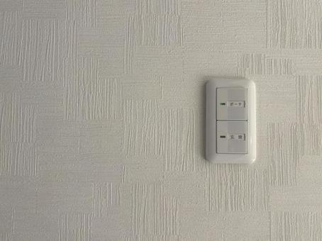 白い壁に玄関照明のスイッチの写真