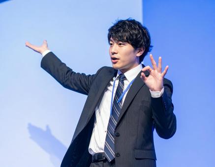 ステージ上で堂々とプレゼンする男性 ステージ上で堂々とプレゼンする男性の写真