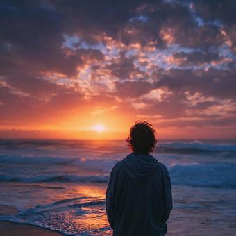 穏やかな波打ち際で夕焼けを見つめる人物 穏やかな波打ち際で夕焼けを見つめる人物の写真