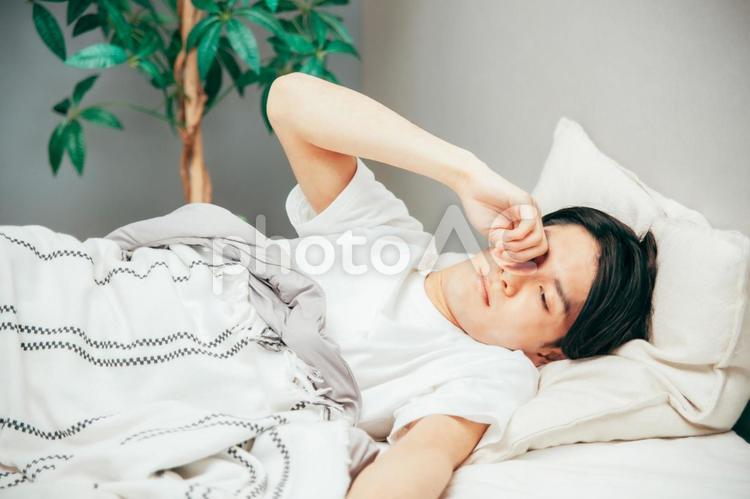寝室でだるそうな男性 眠い,だるい,不眠症の写真素材