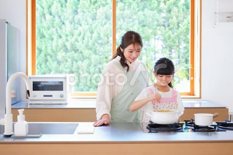 カレーをお玉で混ぜる女の子 母,娘,女の子の写真素材