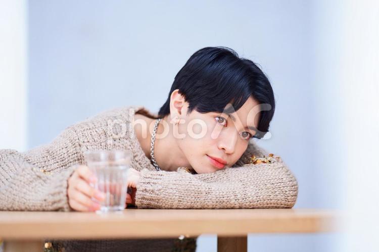 右手でコップを持つ真顔の男性 男性,腕枕,ポーズの写真素材
