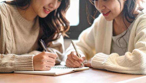 メモ帳を用いて筆談をする若い女性の友人 メモ帳を用いて筆談をする若い女性の友人の写真