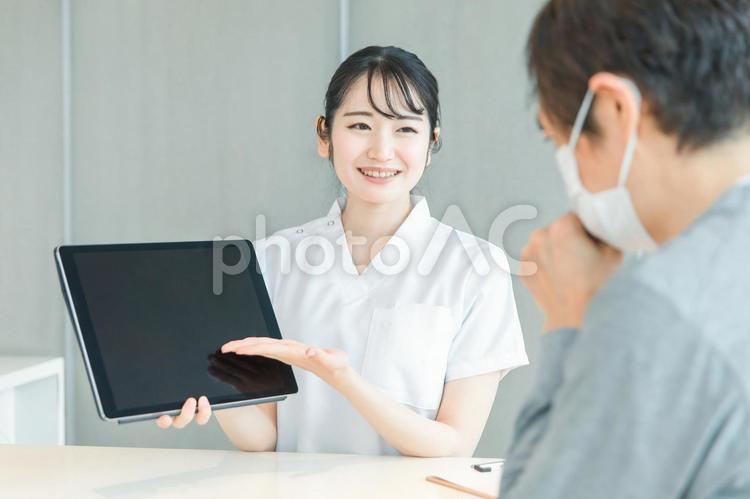 タブレットPCで受付する白衣の女性と患者 病院,受付,レセプトの写真素材