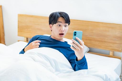 携帯を見て驚く男性 携帯を見て驚く男性 遅刻,寝坊,驚くの写真素材