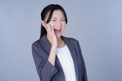 頬に手を当てたスーツを着た女性の写真