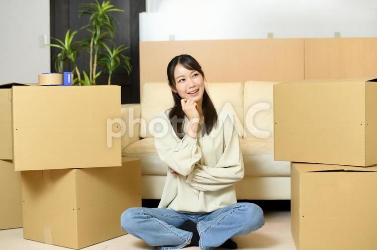 段ボール箱の前で考える笑顔の若い女性 新生活,引っ越し,女性の写真素材