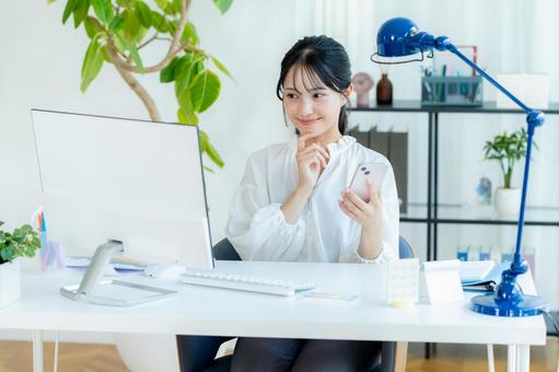 オフィスでスマホを持つビジネスウーマン スマホ,笑顔,ビジネスウーマンの写真素材