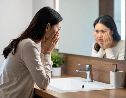 鏡の前で悩む30代の女性の写真