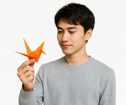 折り鶴を手にする落ち着いた男性の表情 折り鶴を手にする落ち着いた男性の表情の写真