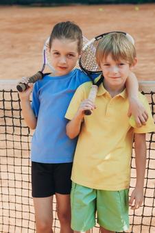 テニスネットの前に立つ子供たち 男の子,女の子,外国人の写真素材