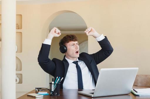 両手でガッツポーズをするスーツの男性 男性,外国人,ノートパソコンの写真素材