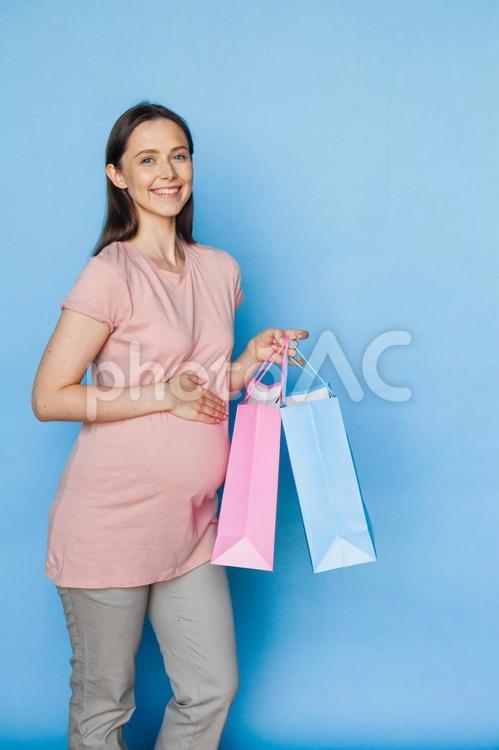 笑顔で紙袋を持っている妊婦さん 女性,人物,ピンクの写真素材