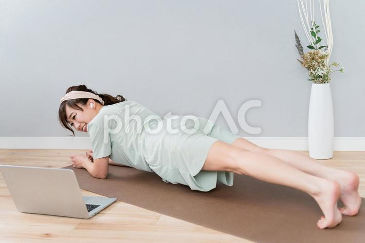 パソコンを見ながら腕立て伏せする女性 腕立て伏せ,プランク,腕立ての写真素材