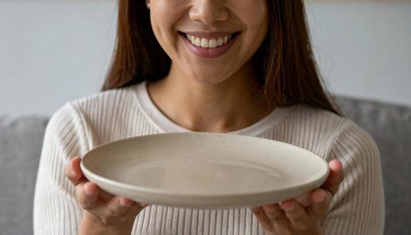 食後、空になったお皿を前に笑顔の女性 食後、空になったお皿を前に笑顔の女性の写真