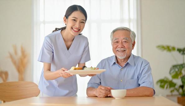笑顔で食事を運ぶ女性介護士と高齢男性 笑顔で食事を運ぶ女性介護士と高齢男性の写真