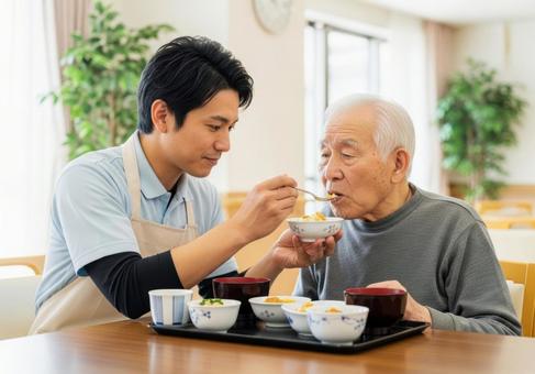 男性介護士が高齢男性に食事介助する場面 男性介護士が高齢男性に食事介助する場面の写真