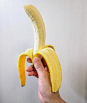 右手に川を剥いたバナナを持つ 果物 右手に川を剥いたバナナを持つ 果物の写真