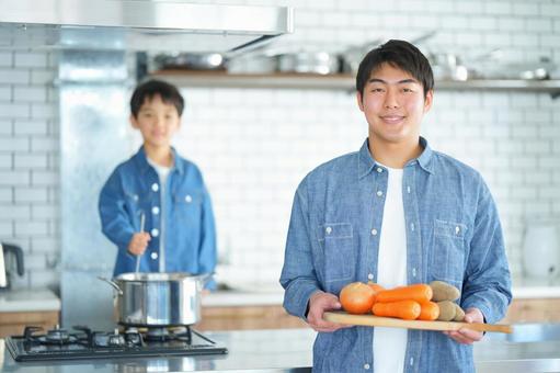 鍋をかき回す男の子と野菜を持っている男性 鍋をかき回す男の子と野菜を持っている男性の写真