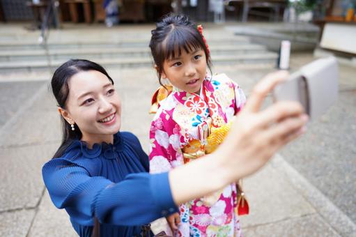 母と娘がスマホで自撮りする七五三のひととき 七五三,お参り,七五三参りの写真素材