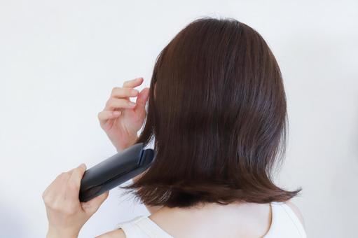 ストレートアイロンを使う女性 ストレートアイロンを使う女性 ヘアケア,アイロン,ストレートの写真素材