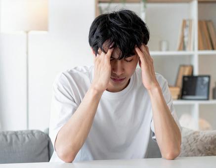 頭を抱える若い男性 頭を抱える若い男性の写真