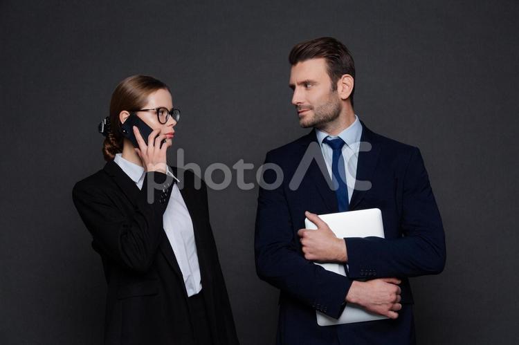 電話する女性とタブレットを持った男性が向かい合っている様子 男女,女性,男性の写真素材