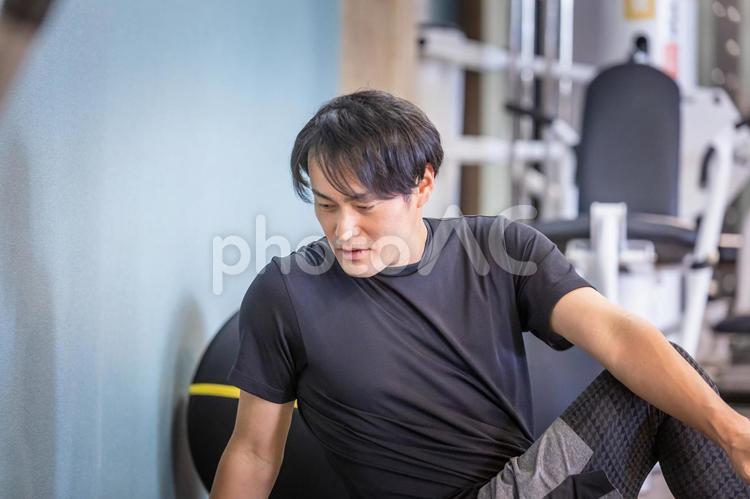 スポーツジムでストレッチする男性（ひねる） ストレッチ,柔軟運動,柔軟体操の写真素材